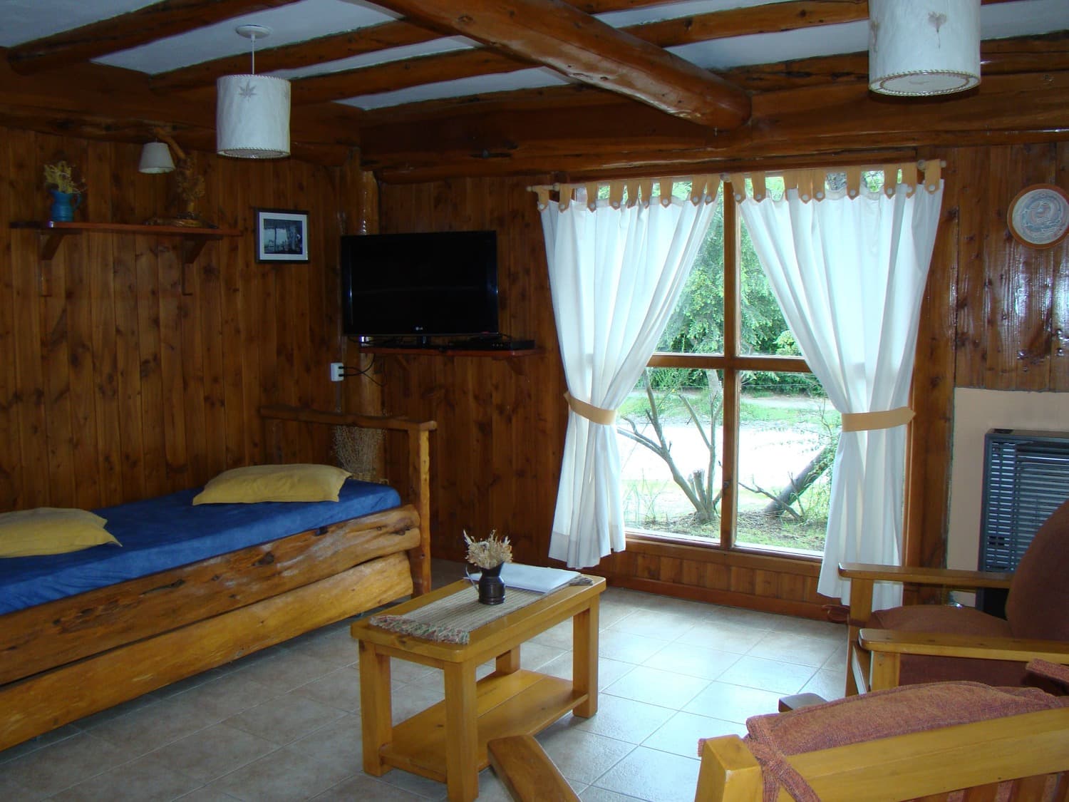 Sala de estar y cama en planta baja de La Casona de Cabañas Denise